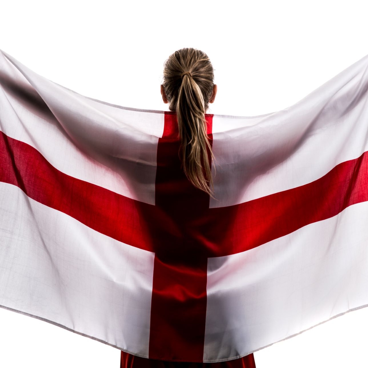 A woman with long blond hair with her back to the camera and arms raised is holding an England flag behind her